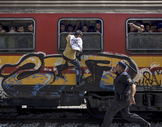 A police officer tries to stop someone from boarding a train through a window at Gevgelija train station in Macedonia, close to the border with Greece (Thomson Reuters/Stoyan Nenov - August 15, 2015).