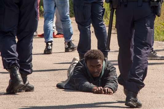 Un migrant allongé au sol entouré par des policiers français le 1er juin 2017 à Calais. PHILIPPE HUGUEN / AFP